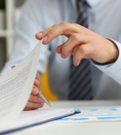 Cropped photo of young businessman holding a pen and signing a document in office